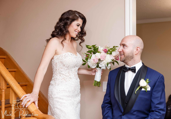 Bride descending a staircase with a bouquet of flowers, greeting her groom